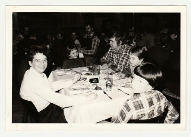 Vintage photo shows a group of people in the restaurant. clipart
