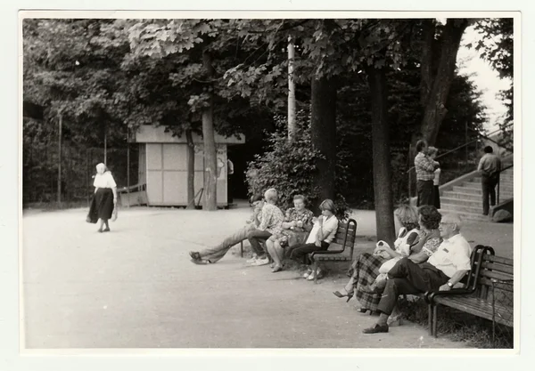 Archiwalne zdjęcie pokazuje, że ludzie siedzą na ławkach w parku miejskim. — Zdjęcie stockowe