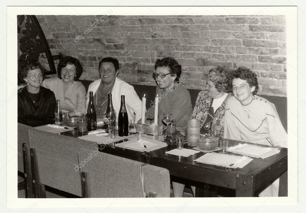 Vintage photo shows a group of people in a wine bar.
