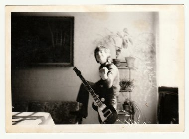 Vintage fotoğraf genç bir çocuk gitar çalar gösterir. Fotoğraf blurryness vardır.