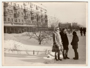Vintage photo shows  girls and boy talk on street in winter. clipart