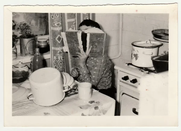 Foto vintage mostra um menino pequeno cobre o rosto por livro . — Fotografia de Stock