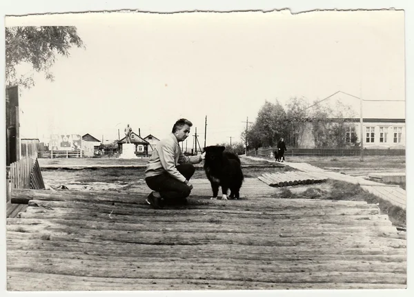 Oldtimer-Foto zeigt Mann streichelt Hund auf der Straße. — Stockfoto