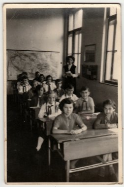 Vintage photo shows pupils sit at the school desks in classroom. clipart