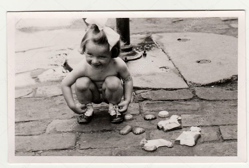 Retro photo shows girl plays with retro sand toys in the back yard.