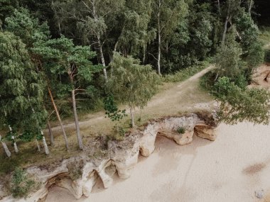 Deniz dalgalarının havadan görünüşü turkuaz deniz suyuyla sahildeki kayalara çarpıyor. Letonya kıyı şeridindeki inanılmaz kayalık deniz manzarası. İHA atışı.
