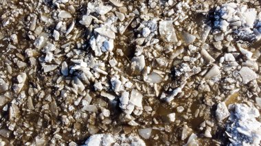 Kırık beyaz buzun soyut dokusu ve kışın koyu su. Bahar geliyor. Donmuş yüzeyin hava görüntüsü.