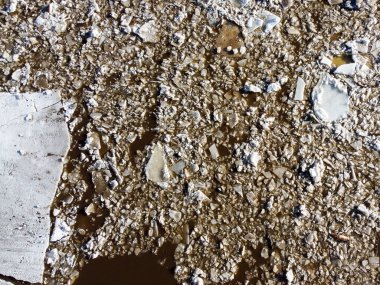 Kırık beyaz buzun soyut dokusu ve kışın koyu su. Bahar geliyor. Donmuş yüzeyin hava görüntüsü.