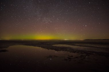 Gölün ve tepelerin üzerinde kuzey ışıkları. Gece Aurora Kuzeyde gökyüzünde.