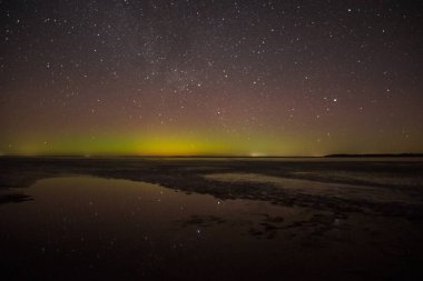 Gölün ve tepelerin üzerinde kuzey ışıkları. Gece Aurora Kuzeyde gökyüzünde.