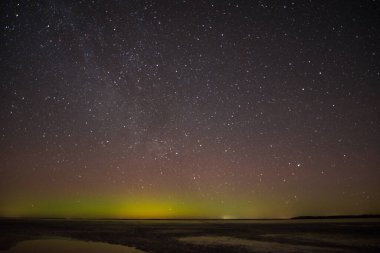 Gölün ve tepelerin üzerinde kuzey ışıkları. Gece Aurora Kuzeyde gökyüzünde.