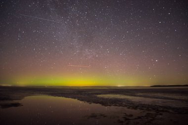 Gölün ve tepelerin üzerinde kuzey ışıkları. Gece Aurora Kuzeyde gökyüzünde.