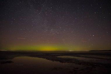 Gölün ve tepelerin üzerinde kuzey ışıkları. Gece Aurora Kuzeyde gökyüzünde.