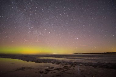Gölün ve tepelerin üzerinde kuzey ışıkları. Gece Aurora Kuzeyde gökyüzünde.
