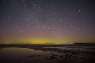 Gölün ve tepelerin üzerinde kuzey ışıkları. Gece Aurora Kuzeyde gökyüzünde.