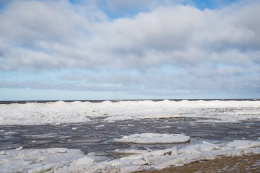 Mavi gökyüzüyle deniz kıyısı ve buz küpleri.