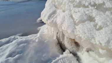 Güneşli bir kış gününde deniz kenarında mavi gökyüzü olan karlı kayalar yığını. Kış manzarası