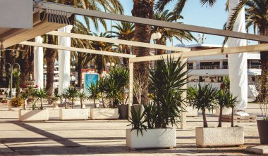 Eski şehrin günbatımında caddenin inanılmaz manzarası. Asfalt kaldırımda duran çiçekli çömlekler. Güneş, taş saksıların üzerinde parlıyor. Hırvatistan 'a git. Sokak görünümü