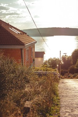 Hırvatistan 'da güzel bir sokak manzarası, kırmızı bir ev ve denizde gün batımı. Yaz manzarası