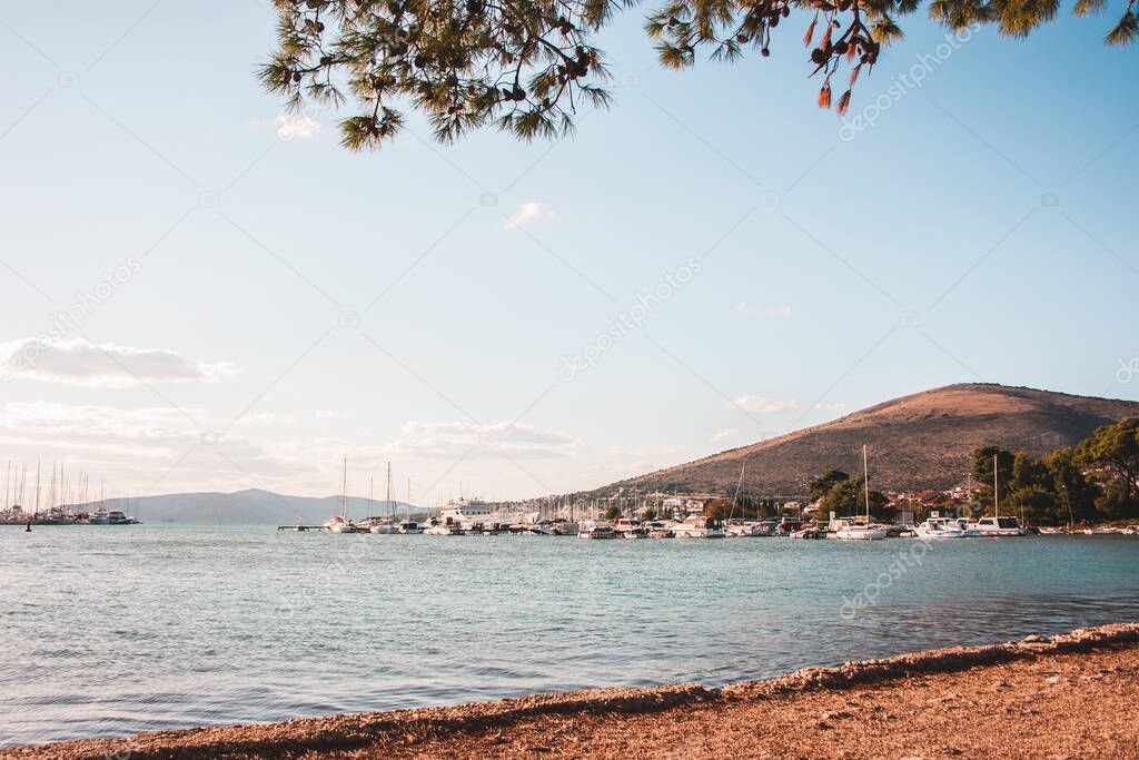 Beautiful beach view in summer with blue skies and blue water in Croatia. Sailing boats and yachts and a mountain can be seen in the distance. Summer landscape.