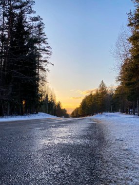 Gün batımında karlı bir ormanda kış yolu. Kış manzarası