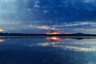 Günbatımı gökyüzü arkaplanı. Gölün üzerinde akşam gökyüzü bulutları olan dramatik altın gün batımı. Güneşin doğuşunda çarpıcı gökyüzü bulutları. Gökyüzü manzarası. Panoramik manzara. Yaz manzarası