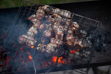 Kırmızı kömürlü metal bir ızgarada et kızartıyorum.