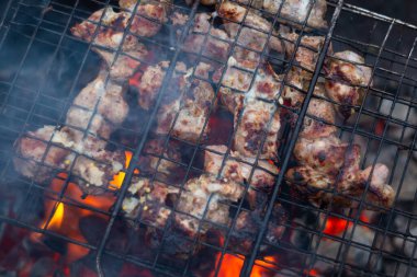 Kırmızı kömürlü metal bir ızgarada et kızartıyorum.