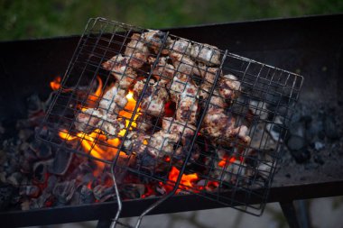 Kırmızı kömürlü metal bir ızgarada et kızartıyorum.