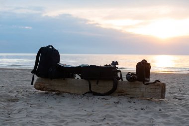 Fotoğraf ekipmanları. Bir fotoğraf çantası. Gün batımında kumsalda bir tezgah..