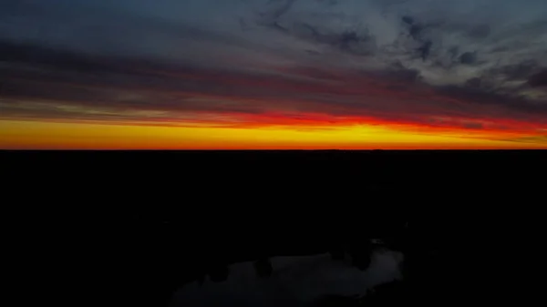 地面に湖の反射とドローンビューからの美しいオレンジと赤の夕日の景色 空中風景 — ストック写真