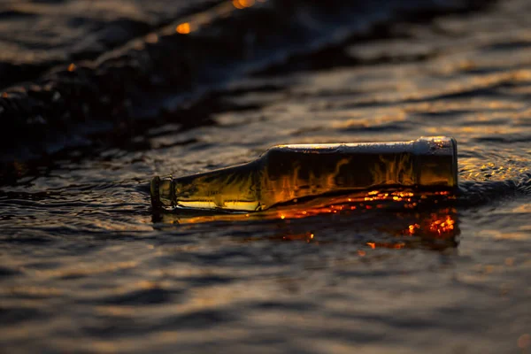 Bottiglia Birra Rovesciata Acqua Mare Tramonto Con Bokeh Sullo Sfondo — Foto Stock