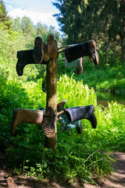 夏天温暖的日子里 绿草碧蓝的天空 泥泞的小径上的木制看台上 一双肮脏的橡胶靴在河边走着 — 图库照片