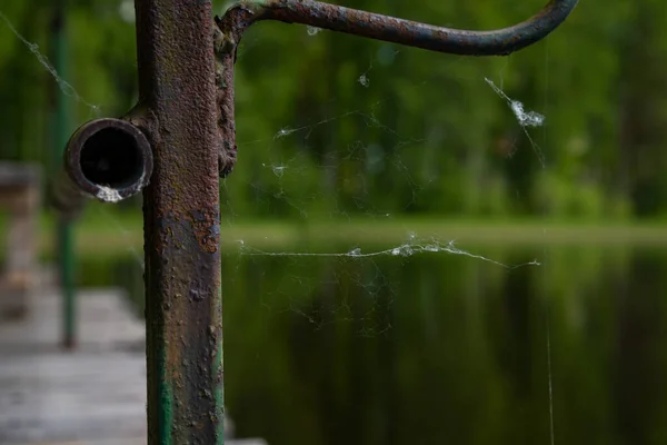 白色蜘蛛网在生锈的棕色金属棒上的特写 — 图库照片