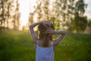 Letonya 'da yaz ortası: Ligo kutlaması - güneşli bir günde çiçek tacı takan genç bir kız.