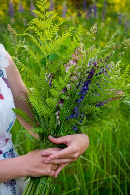 Yaz ortasında elinde bir buket lupin çiçeği tutan güzel bir kadın.