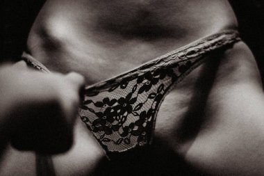 Erkek eli bir kadının dantel iç çamaşırını tutar. Görüntüyü kapat