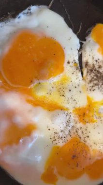 Sıcak tavada kızaran yumurtalar, yumuşak beyazlar ve yağlı yumurtaların yakın çekim videosu. Kahvaltı, yemek pişirme, gıda endüstrisi ve ticari projeler için mutfak konsepti için mükemmel..