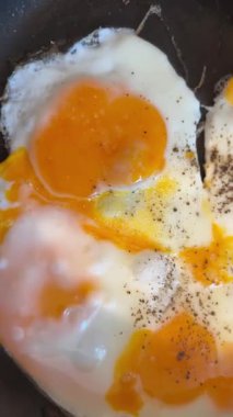 Sıcak tavada kızaran yumurtalar, yumuşak beyazlar ve yağlı yumurtaların yakın çekim videosu. Kahvaltı, yemek pişirme, gıda endüstrisi ve ticari projeler için mutfak konsepti için mükemmel..