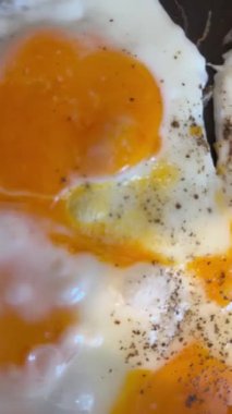 Sıcak tavada kızaran yumurtalar, yumuşak beyazlar ve yağlı yumurtaların yakın çekim videosu. Kahvaltı, yemek pişirme, gıda endüstrisi ve ticari projeler için mutfak konsepti için mükemmel..