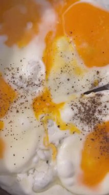 Sıcak tavada kızaran yumurtalar, yumuşak beyazlar ve yağlı yumurtaların yakın çekim videosu. Kahvaltı, yemek pişirme, gıda endüstrisi ve ticari projeler için mutfak konsepti için mükemmel..