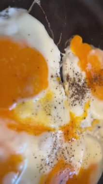 Sıcak tavada kızaran yumurtalar, yumuşak beyazlar ve yağlı yumurtaların yakın çekim videosu. Kahvaltı, yemek pişirme, gıda endüstrisi ve ticari projeler için mutfak konsepti için mükemmel..