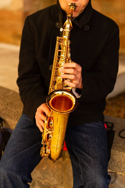 Unrecognizable street musician playing saxophone on the street, concept music