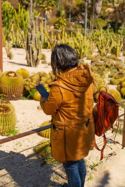 Botanik bahçesinde cep telefonuyla resim çeken bir kız, botanik konsepti.