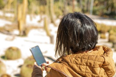 Botanik bahçesinde cep telefonuyla resim çeken bir kız, botanik konsepti.