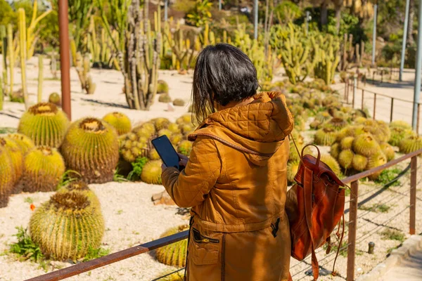 Botanik bahçesinde cep telefonuyla resim çeken bir kız, botanik konsepti.