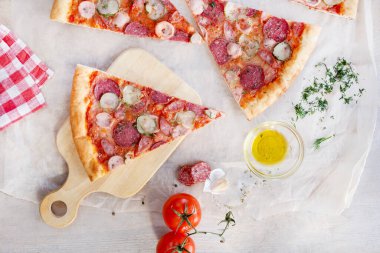 Kesme tahtasında salamlı pizza dilimleri. Sarımsak. Dereotu. Domates. et