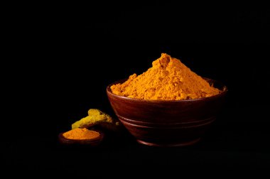 Siyah arkaplanda zerdeçal tozu ve kökleri veya kabukları