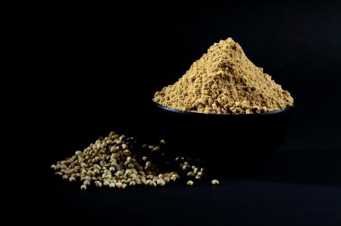 Kişniş tozu ve kişniş tohumları siyah arkaplanda