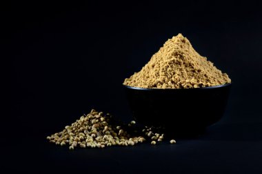 Kişniş tozu ve kişniş tohumları siyah arkaplanda